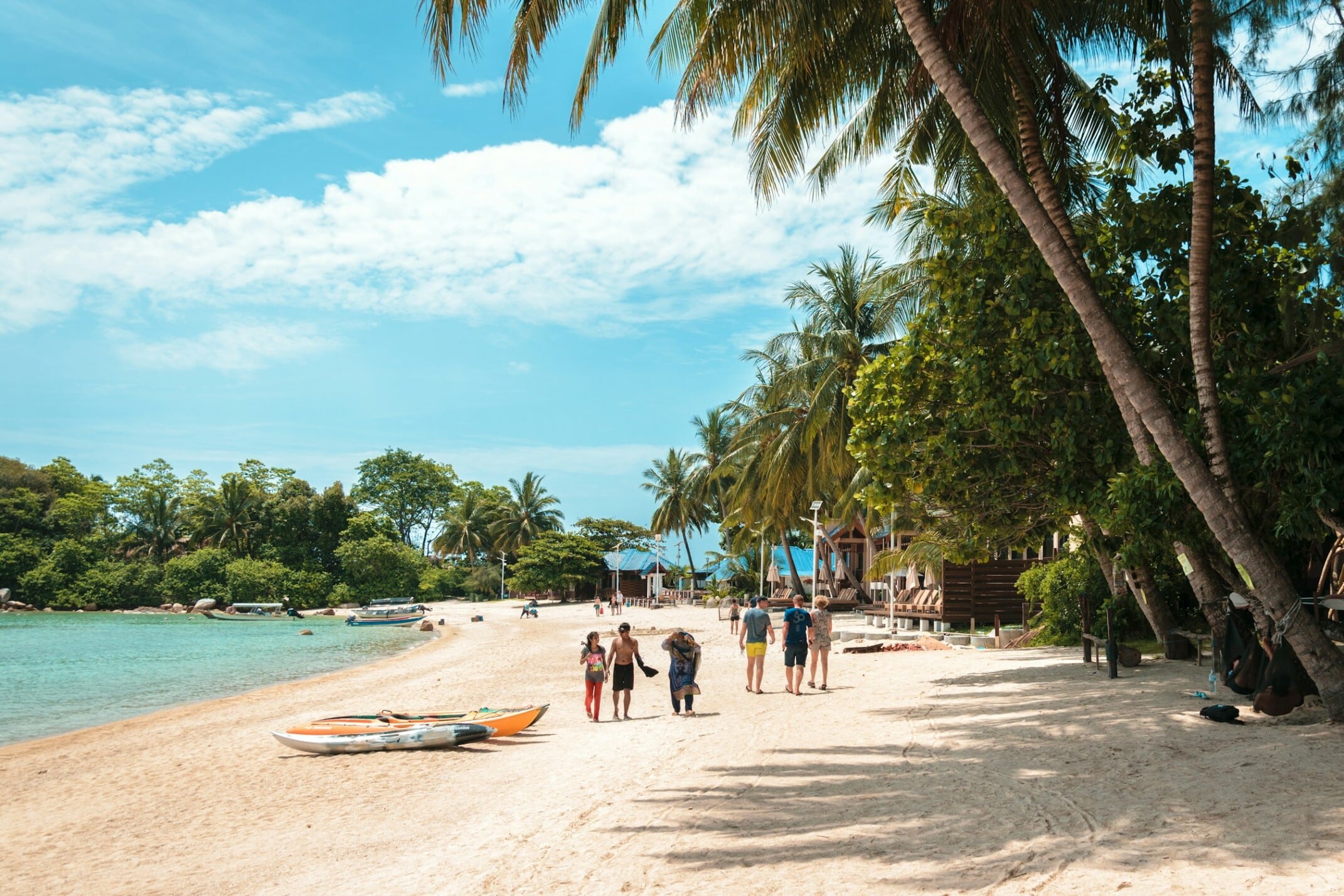 Photo by Job Savelsberg a group of people standing on a beach next to a body of water